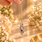 Inner Compass suspended by gold chain between fingertips